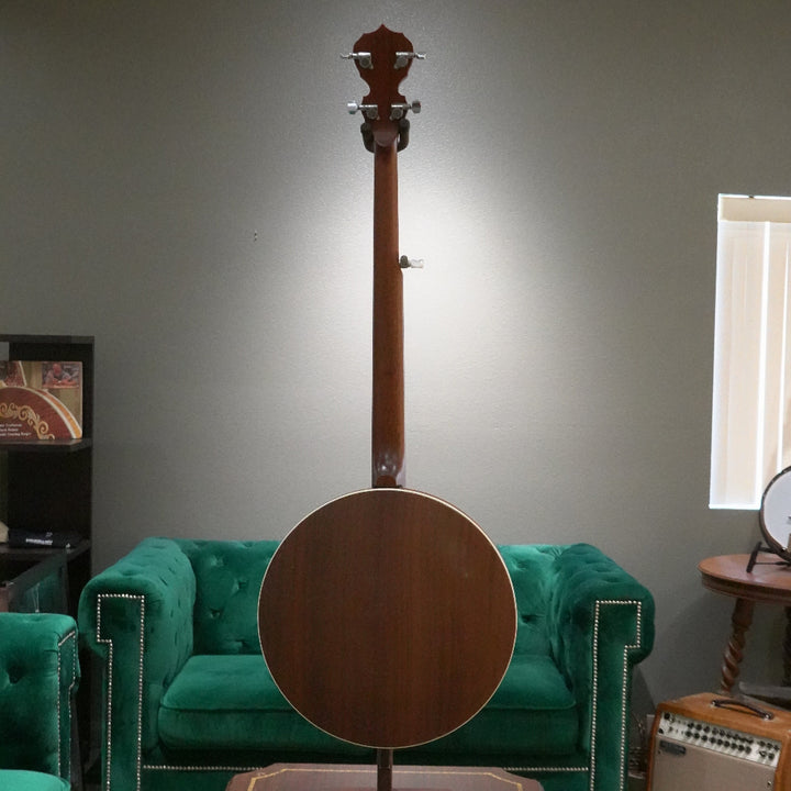 Banjo leaning against a green couch in a room with a window and wall art.