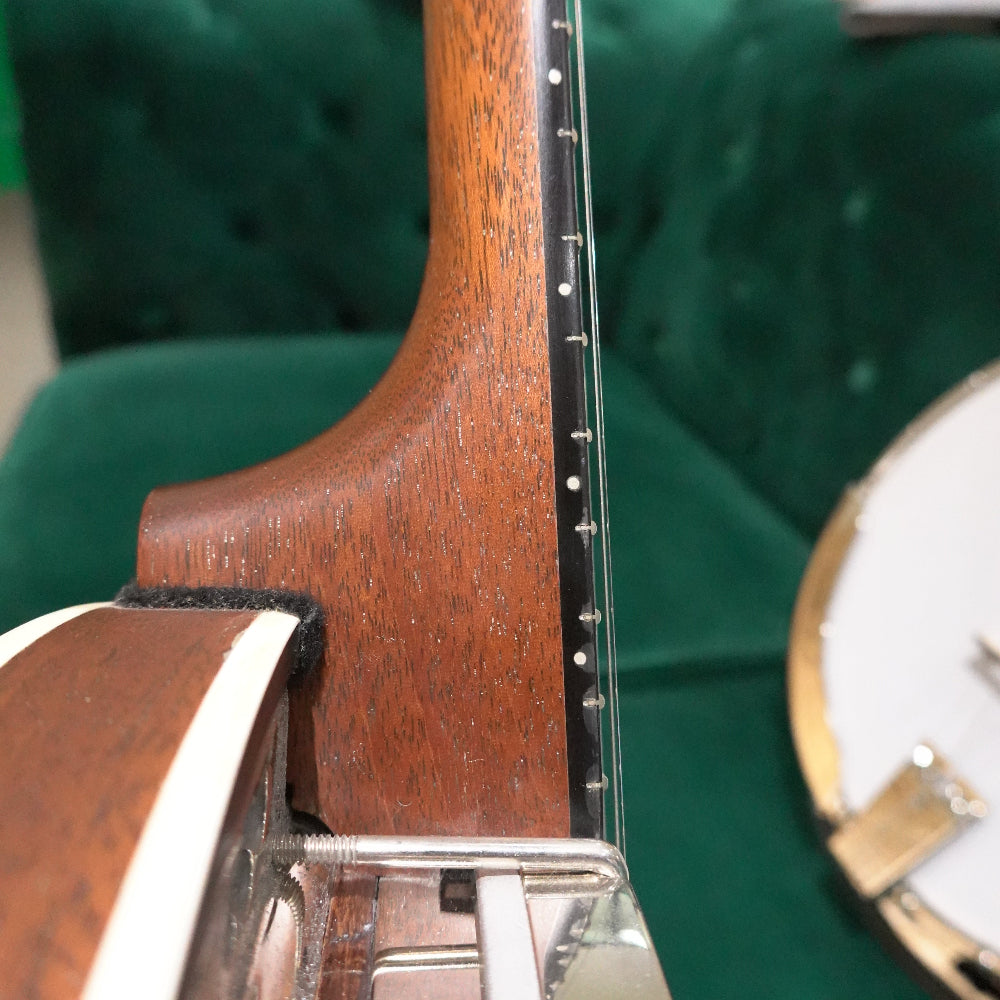 close up of heel of a banjo neck with green background