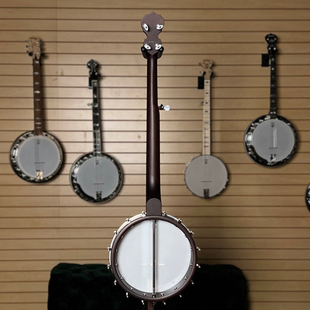 banjo on display in front of wooden wall with banjos. 