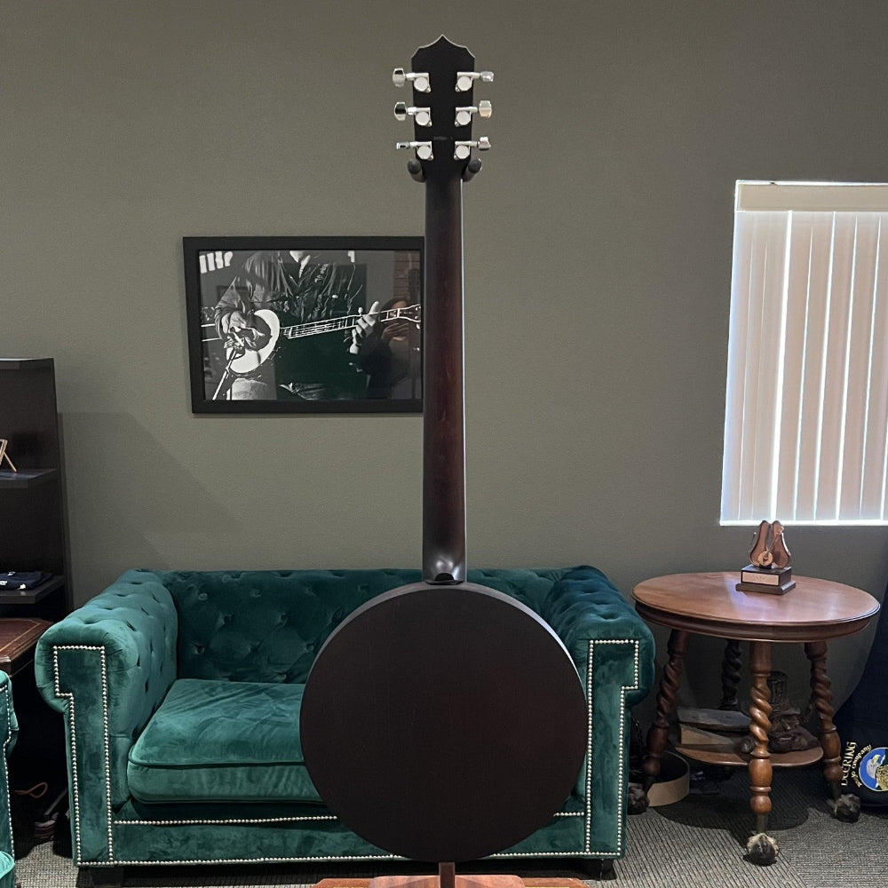 Banjo on a stand in a room with green velvet couches and a window.