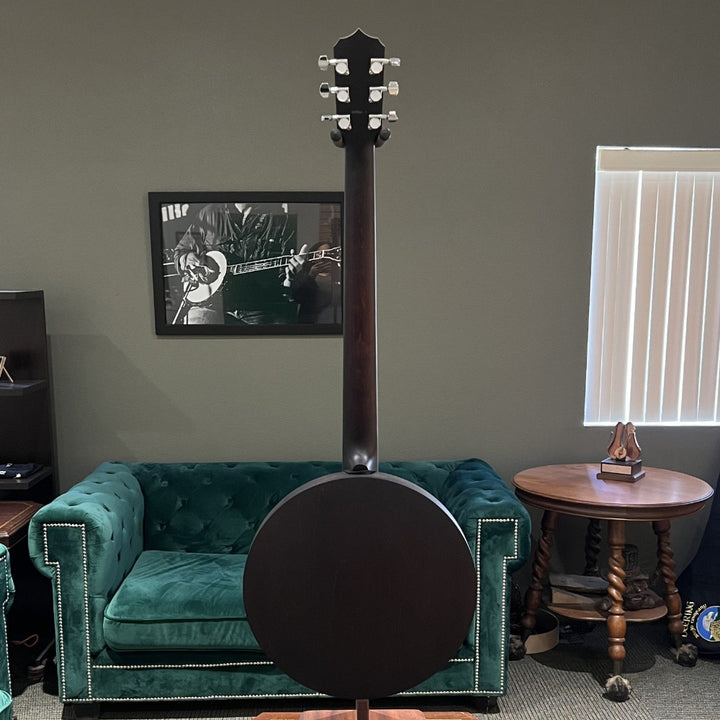 Banjo on a stand in a room with green velvet couches and a window.