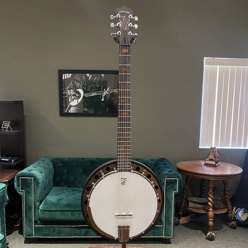 Banjo on a stand in a room with green couch and framed picture on the wall