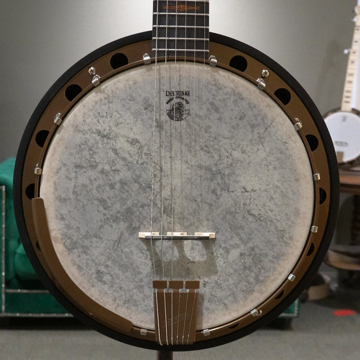 close up of 6 string banjo in front of grey wall and green couch