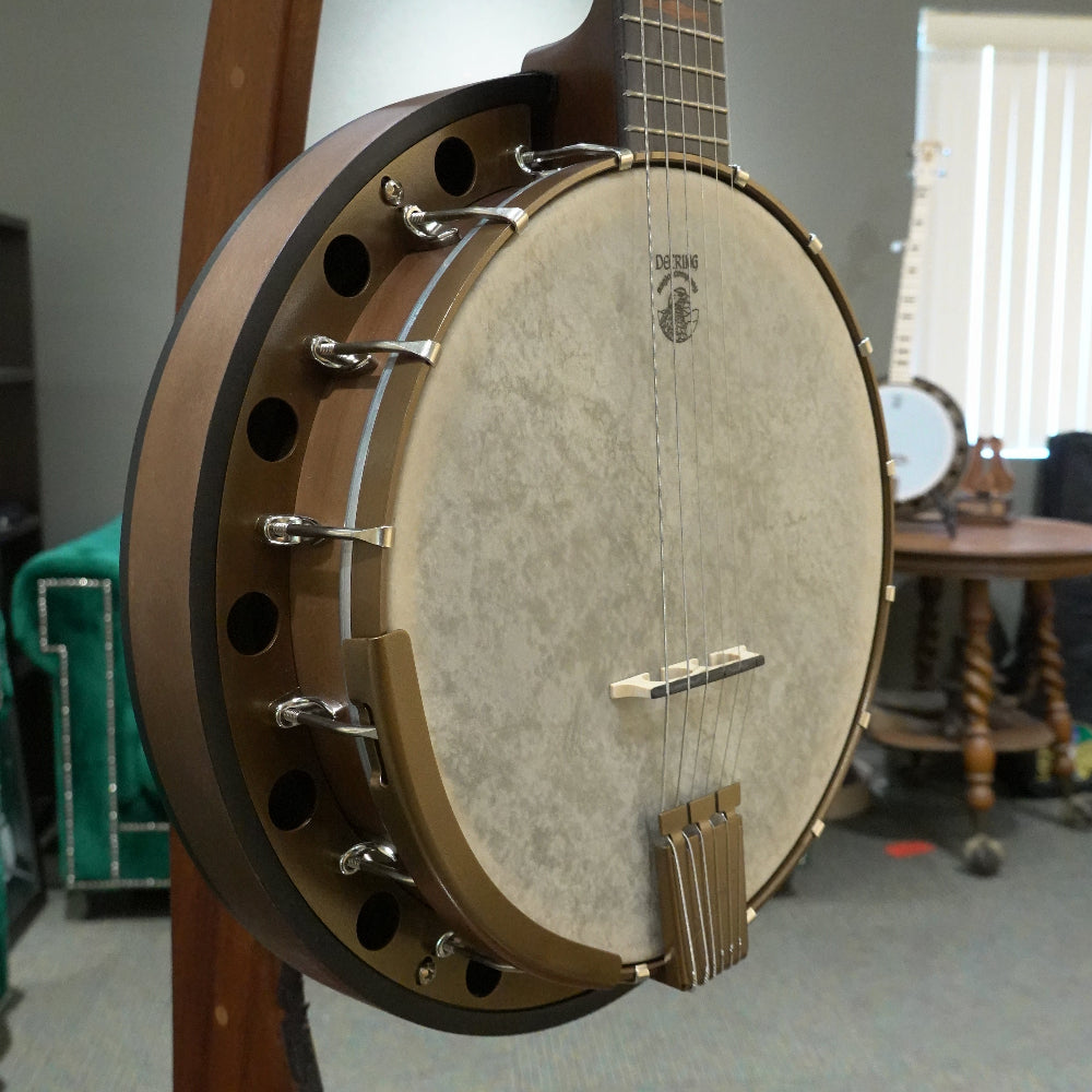 close up of 6 string banjo in front of grey wall and green couch