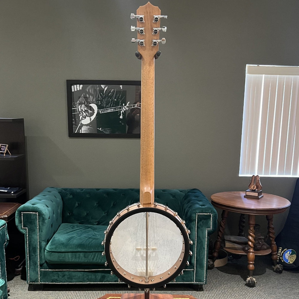 Banjo on a stand in a room with green velvet couch and framed picture on the wall.