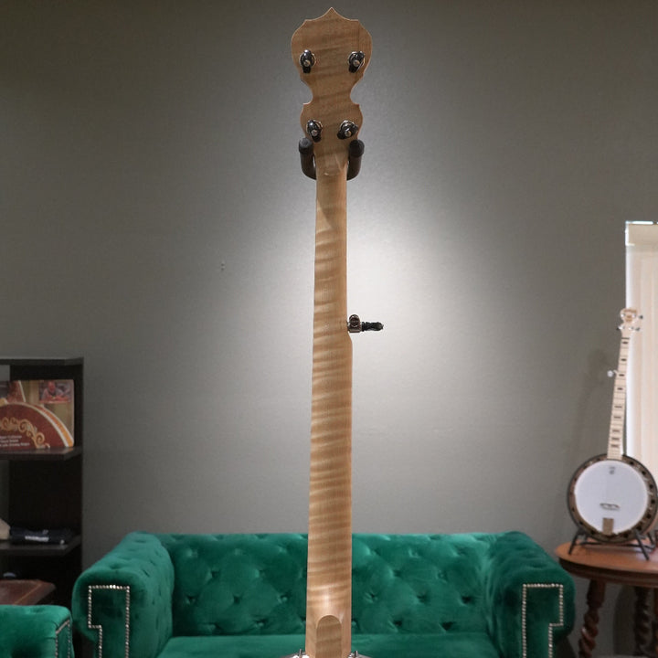 Wooden banjo against a gray wall with a green couch and another banjo in the background.