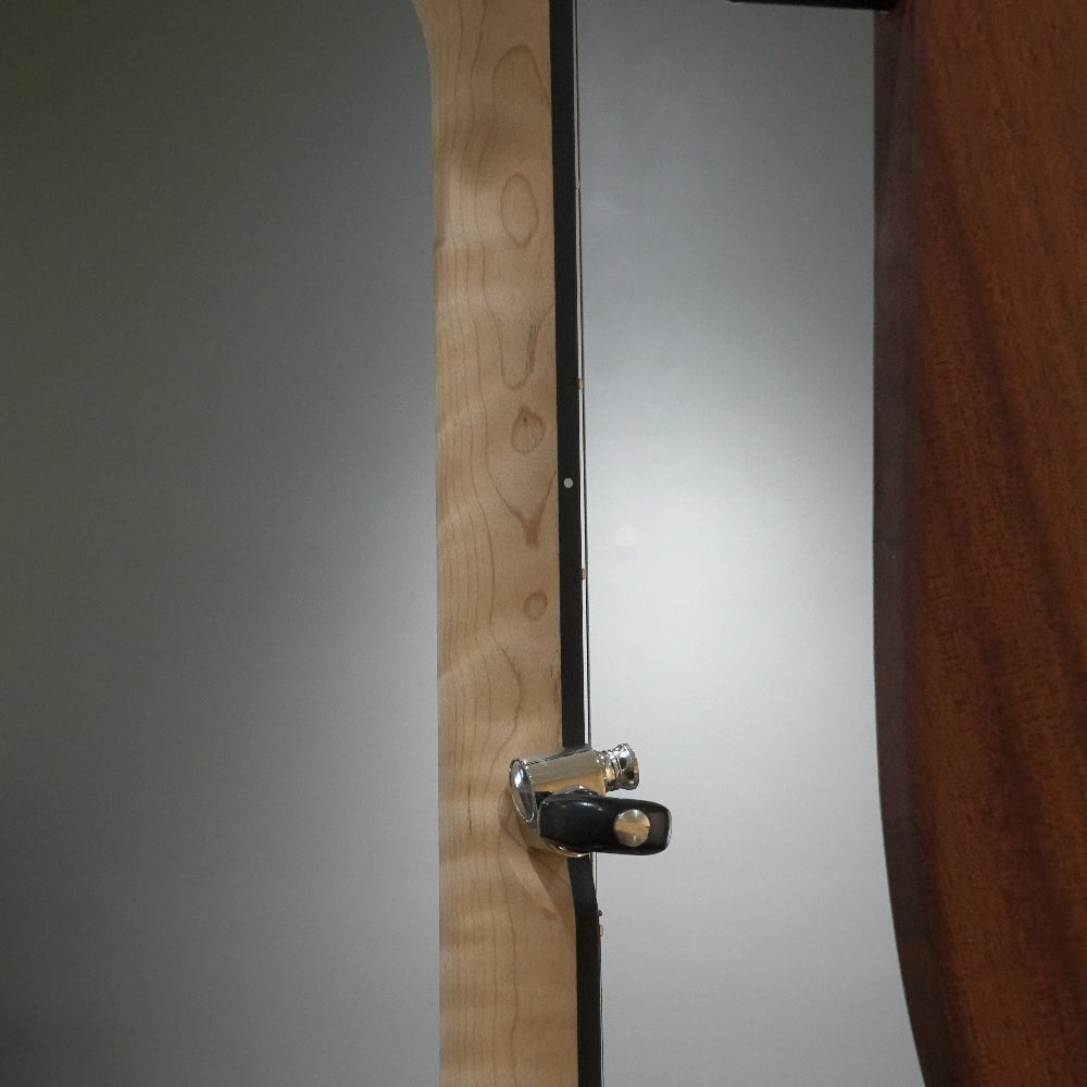 close up of side profile of banjo neck. Natural flame maple with black binding and metal tuner.