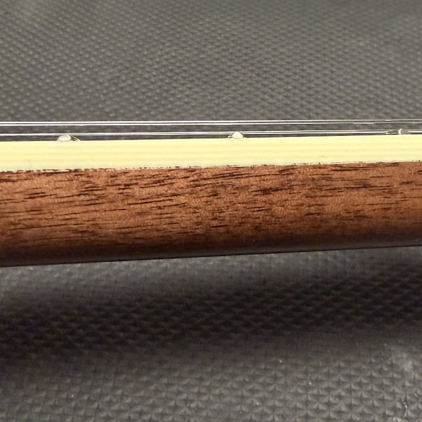 close up of string instrument neck with cream colored binding and wood against a black background