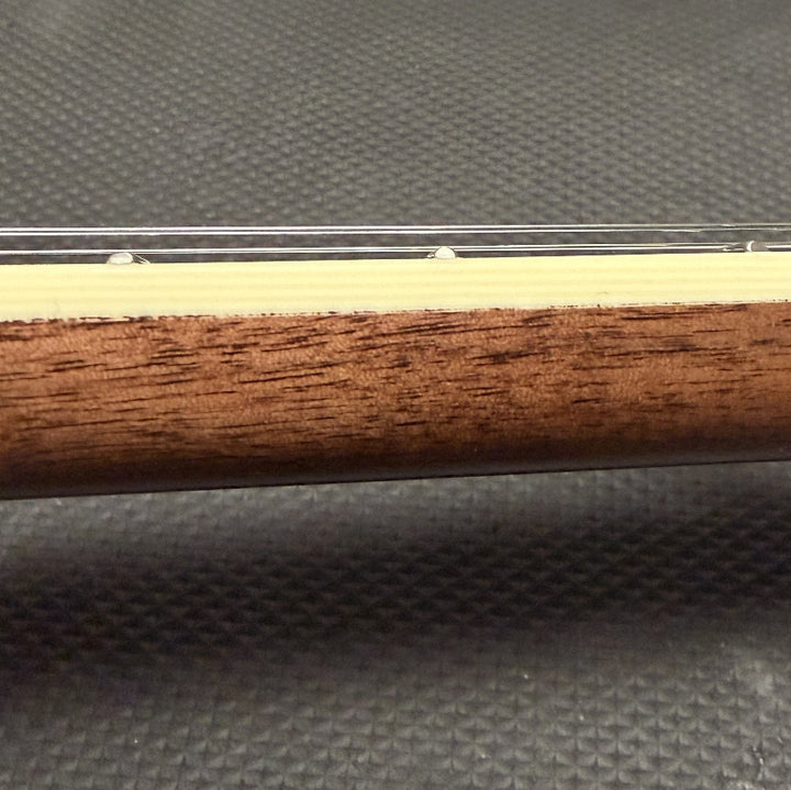 close up of string instrument neck with cream colored binding and wood against a black background