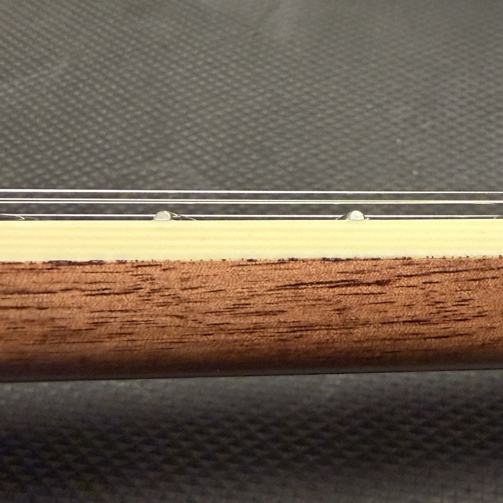 close up of string instrument neck with cream colored binding and wood against a black background
