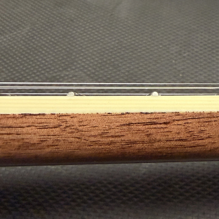 close up of string instrument neck with cream colored binding and wood against a black background