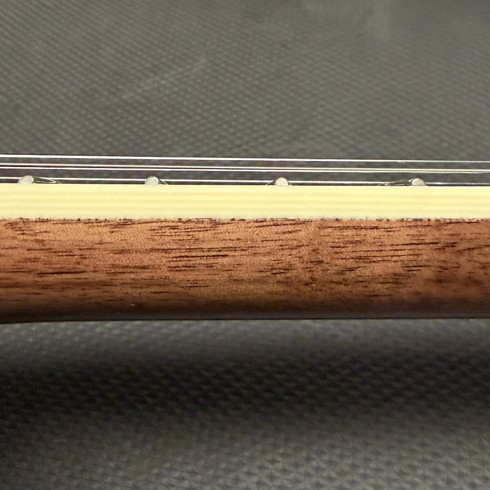 close up of string instrument neck with cream colored binding and wood against a black background