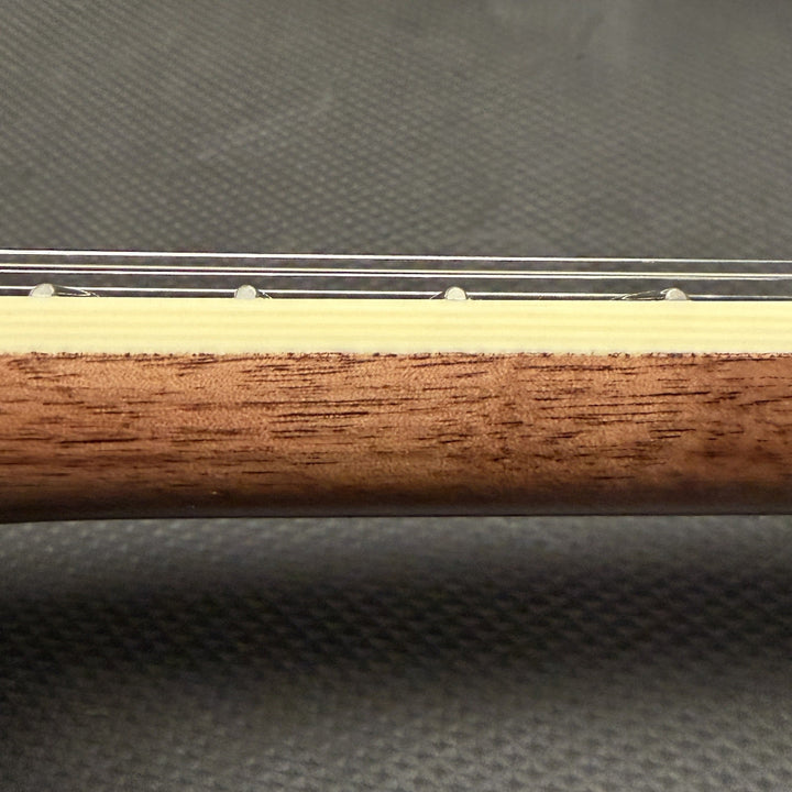 close up of string instrument neck with cream colored binding and wood against a black background