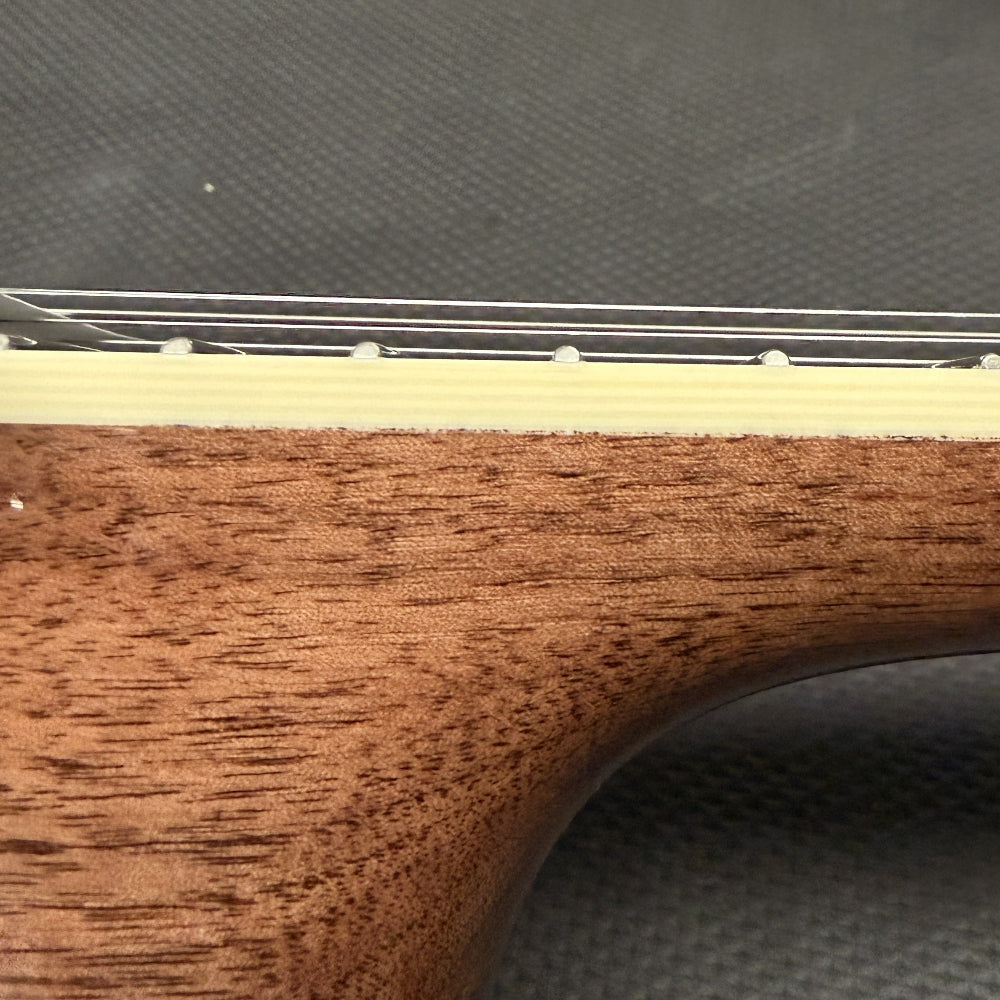 close up of string instrument neck with cream colored binding and wood against a black background