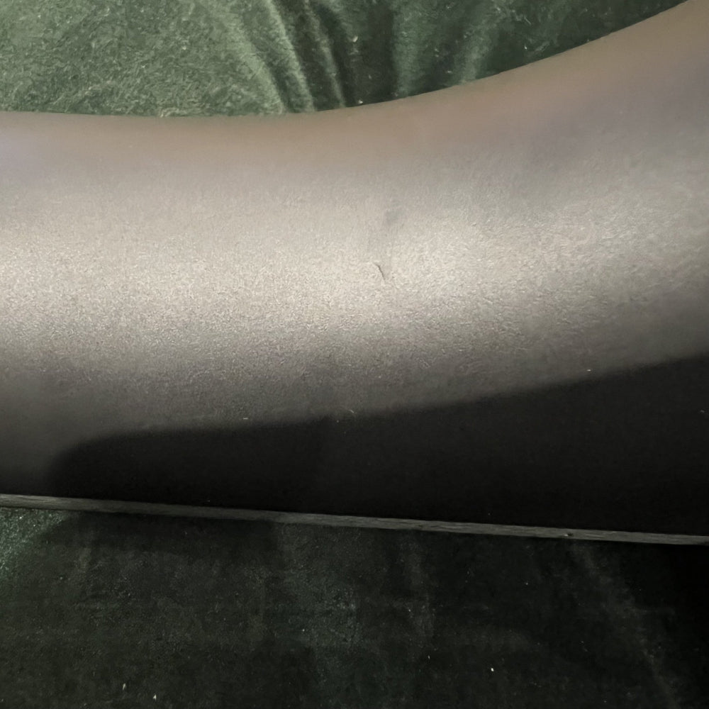 close up of black banjo neck with ding. green velvet background
