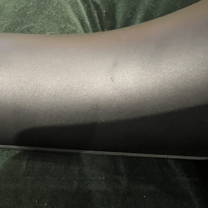 close up of black banjo neck with ding. green velvet background