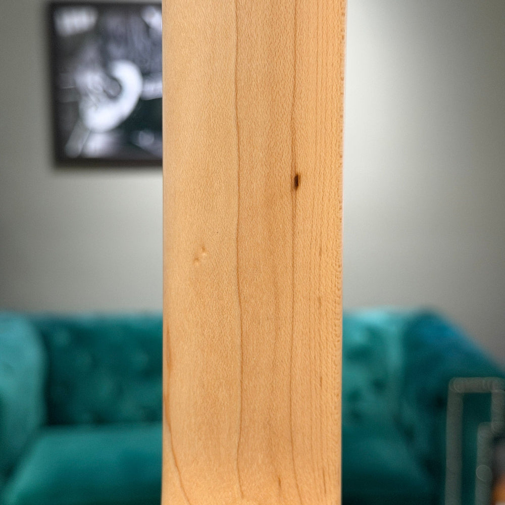 Close-up of a wooden panel with a blurred background featuring a teal couch and framed picture.