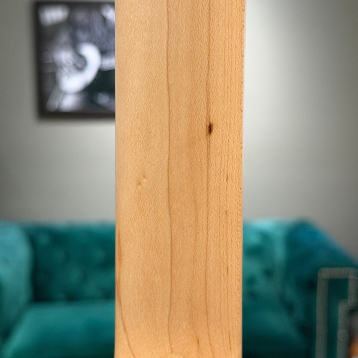 Close-up of a wooden panel with a blurred background featuring a teal couch and framed picture.
