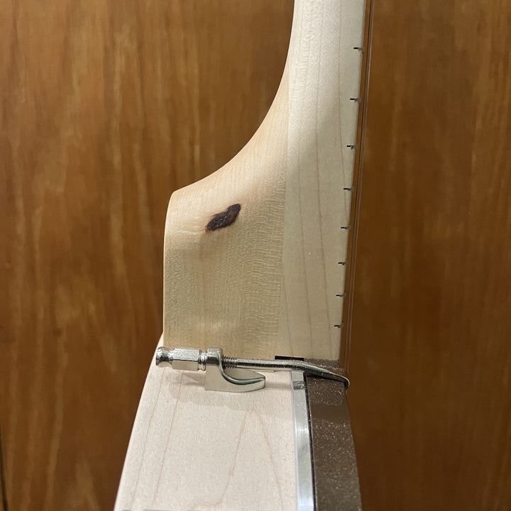 close up of banjo neck with dark knot in the center. 