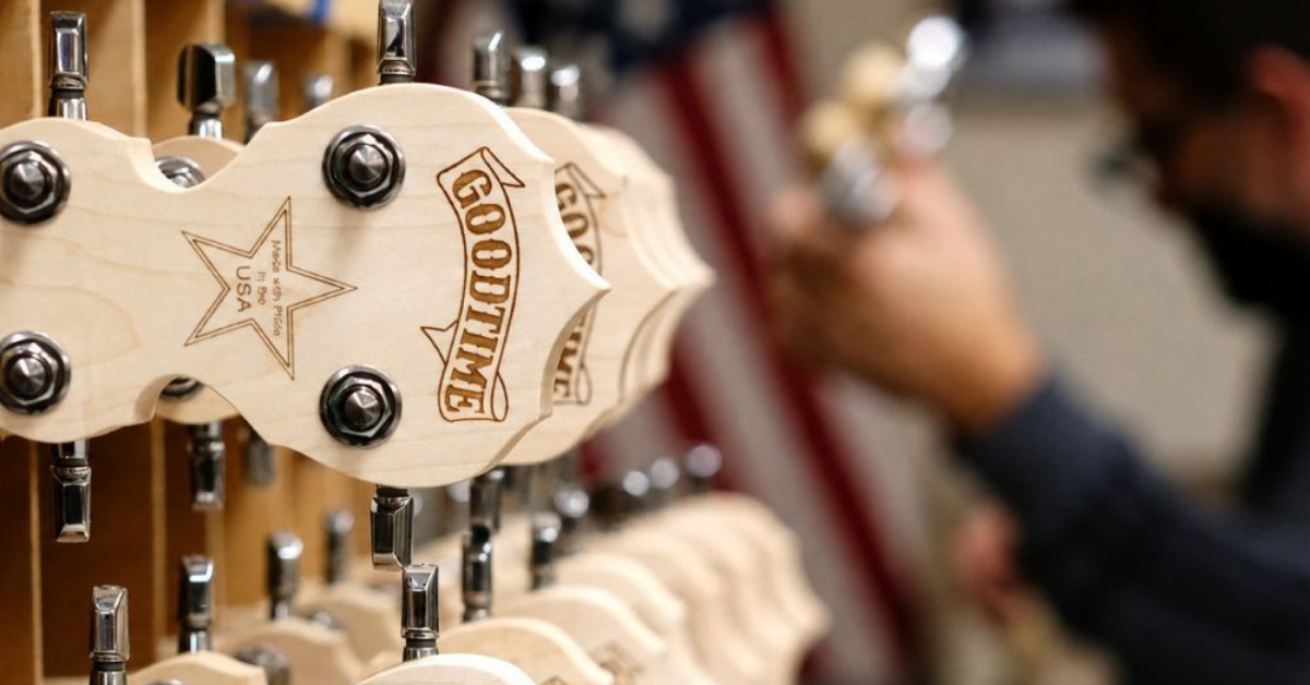 Close-up of Goodtime brand banjo headstocks with a blurred person in the background.