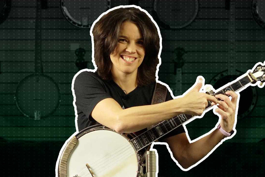 Kristin Scott Benson playing a banjo with a microphone in a room with musical instruments in the background