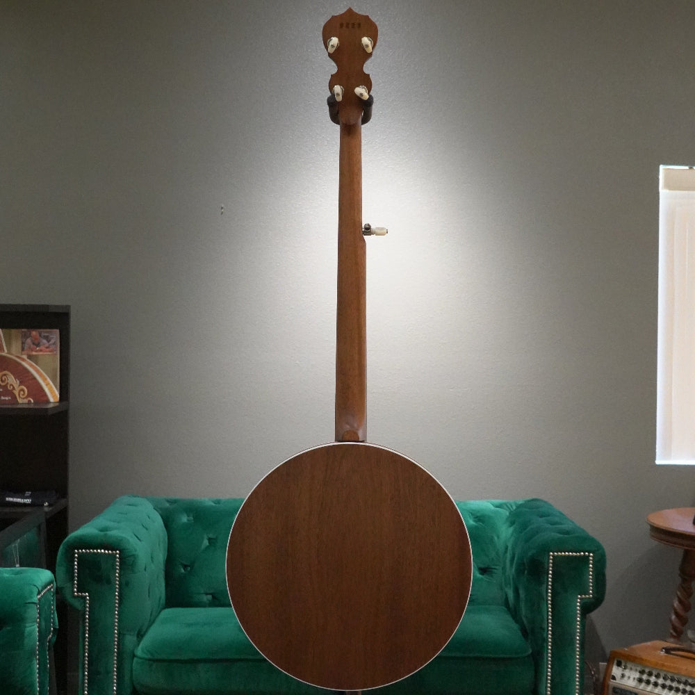 Wooden instrument leaning against a green couch with a neutral wall background