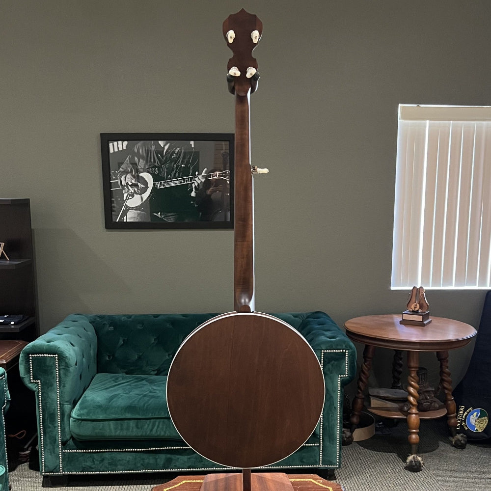 Banjo on a stand in a room with green couches and a window.