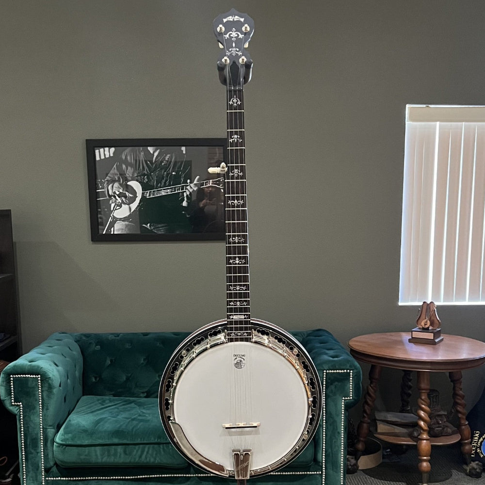 Banjo on a stand in a room with green couches and a window.
