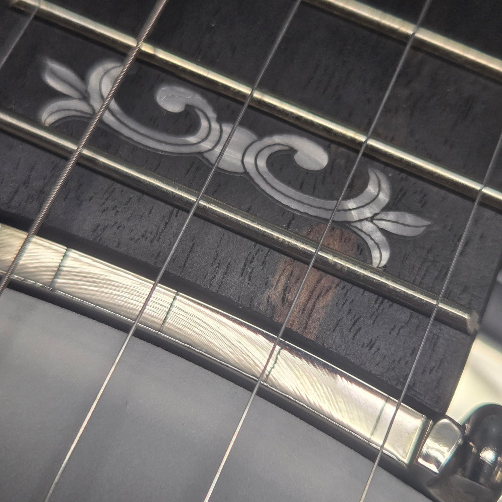 Close-up of a guitar's fretboard with decorative inlay