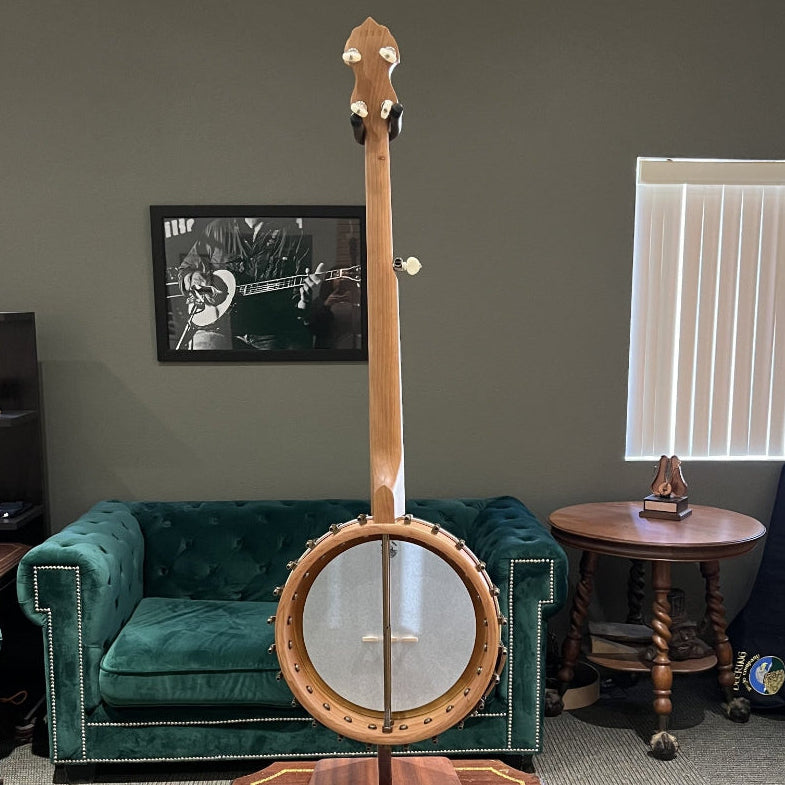 Banjo on a stand in a room with green velvet furniture and a gray wall.