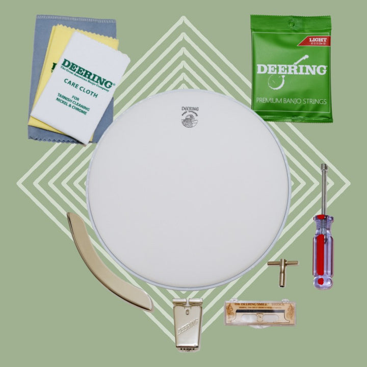 Deering Banjo Care Package front, all three care clothes, one pack of Deering Light gauge strings, truss rod wrench, tr wrench, packaged Deering Smile bridge, Deering True Tone Tailpiece, banjo head, Deering armrest, green background